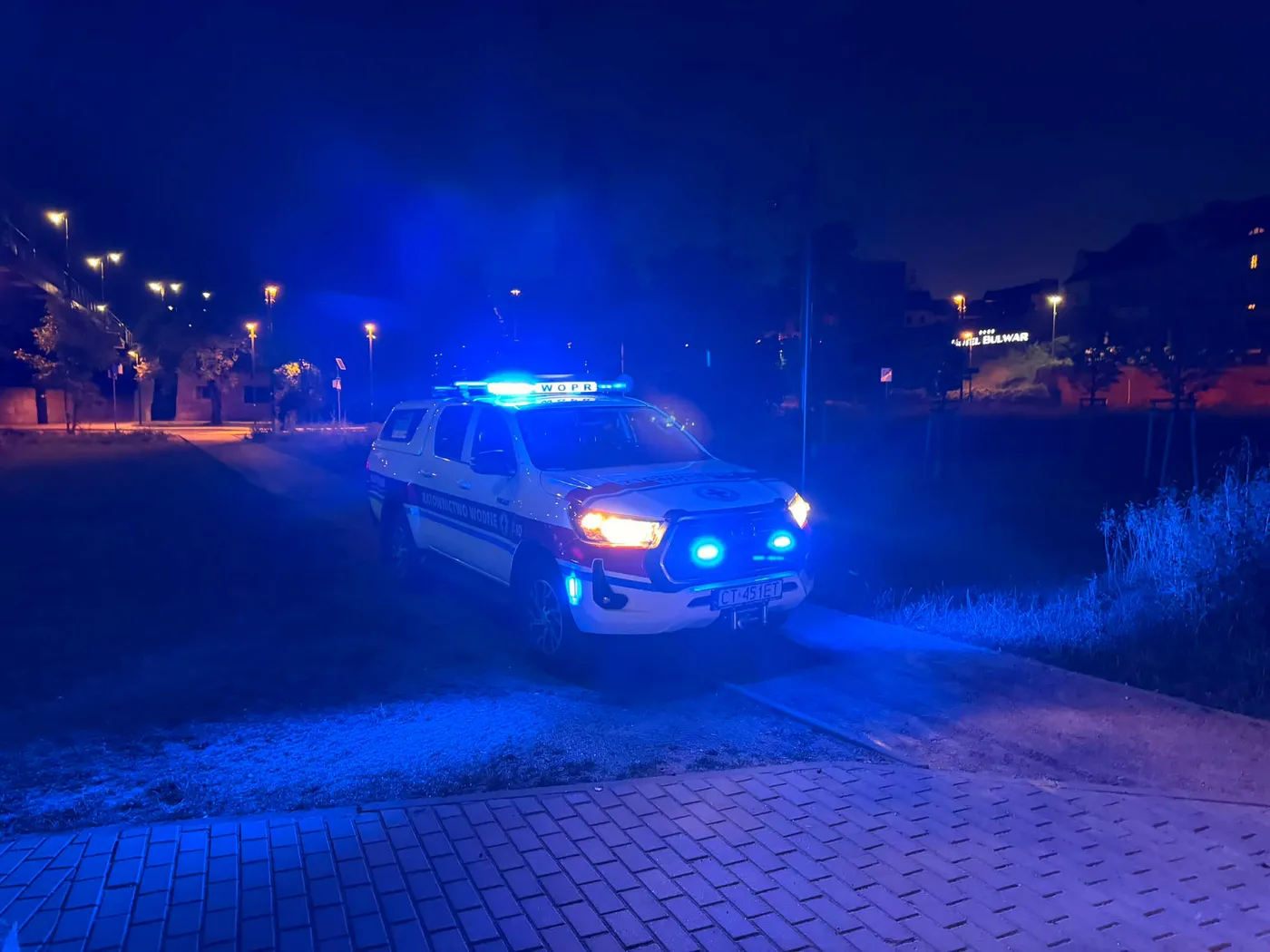 Pickup Toyota Hilux Ratownictwa Wodnego WOPR nocą na drodze, z włączonymi niebieskimi sygnałami świetlnymi